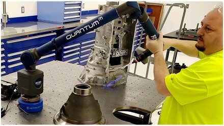 A man operates machinery in a factory setting, focused on his task amidst industrial surroundings.