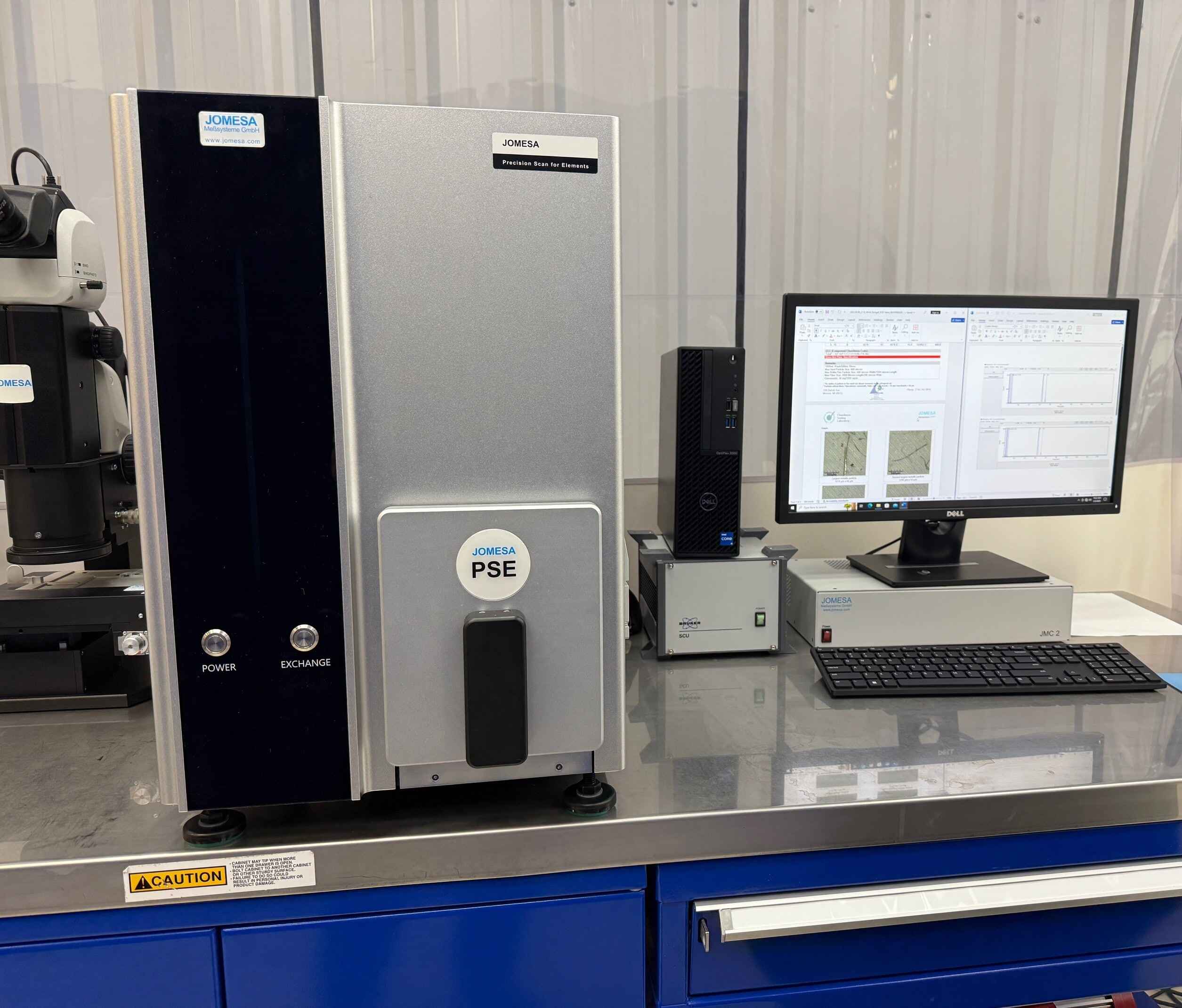 Scanning Electron Microscope SEM-EDS device, showing a sleek computer in a work environment.