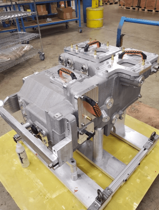 A factory scene showcasing a machine under construction, with workers and equipment actively engaged in the assembly process.