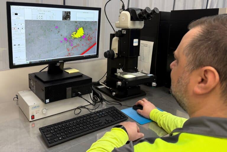 Laboratory staff running an automated particle count on the Jomesa HFD microscope, with the scanned analysis filter and flagged particles on screen